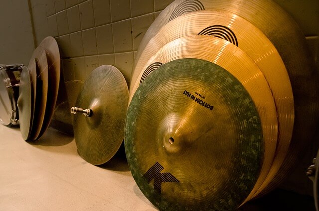 Diiferent cymbals of various sizes leaned up against a wall